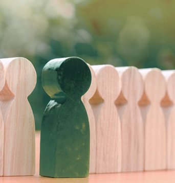 Row of wooden figures with one painted green